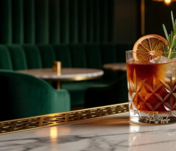 Signature cocktail in a coupe glass on a marble bar with golden reflections